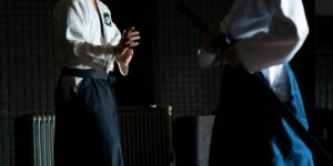 Two adults practicing martial arts in a dimly lit dojo, focused and poised.